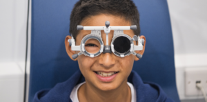 Child smiling while wearing a trial frame during eye exam