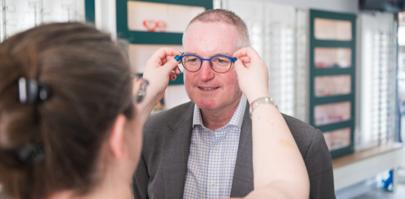 An optician checking the fit of a frame on a patient.