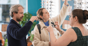 An Ealing based optician helping 2 patients with selecting a pair of sunglasses.