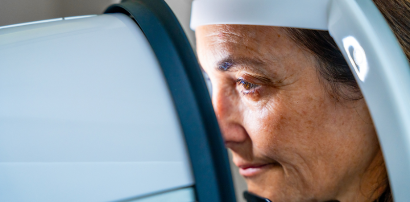A side profile of a woman with her head against an optical testing machine during her eye examination