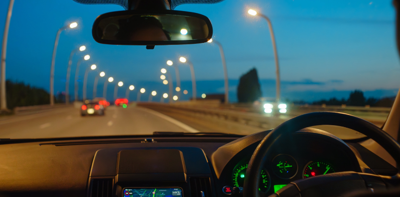 A point of view image from the inside of a car, driving at night.